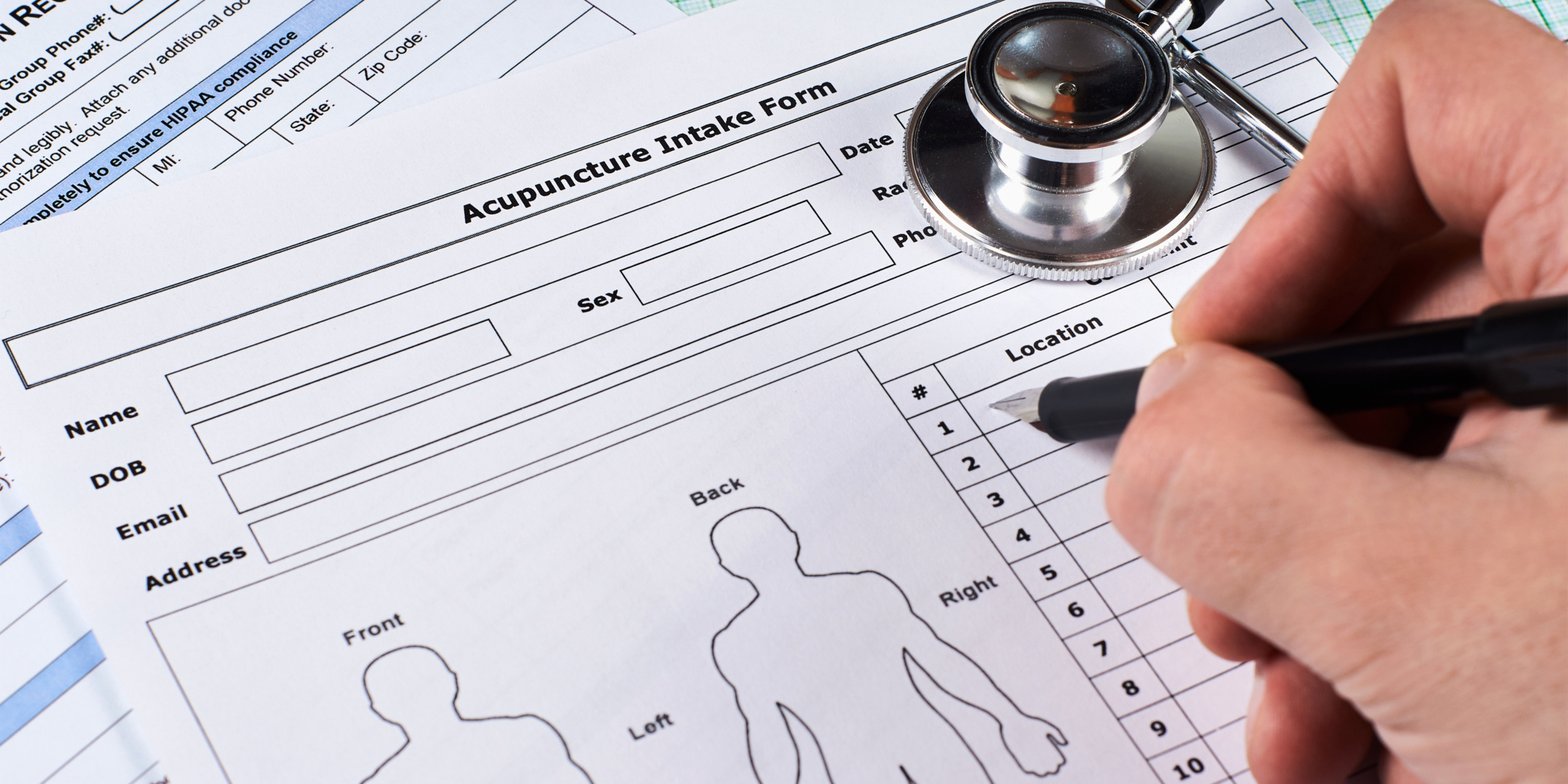 A healthcare provider filling out an acupuncture patient intake form featuring fields for name, date of birth, email, address, sex, and treatment location numbers, alongside front, back, left, and right body diagrams for marking pain areas, with a stethoscope placed on the form.